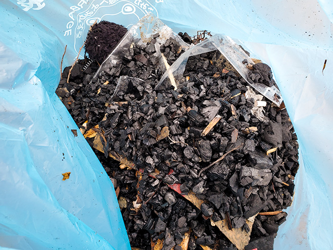 ゴミ袋いっぱいの炭を回収
