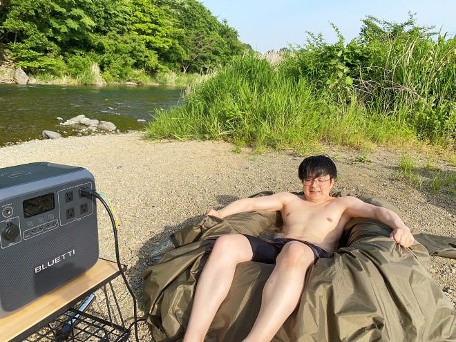 20Lの自作露天風呂に入る水着姿の男