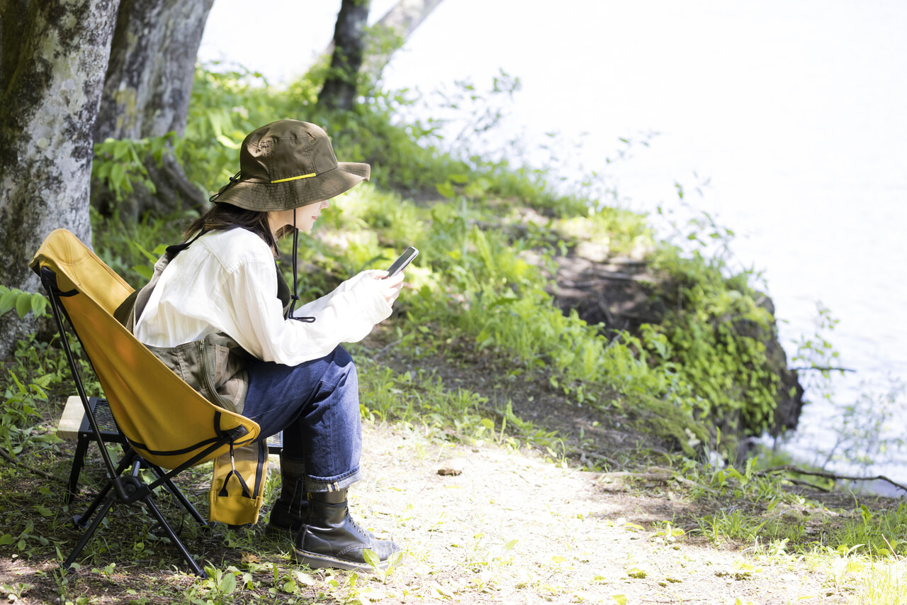 キャンプ場でスマートフォンを見る女性