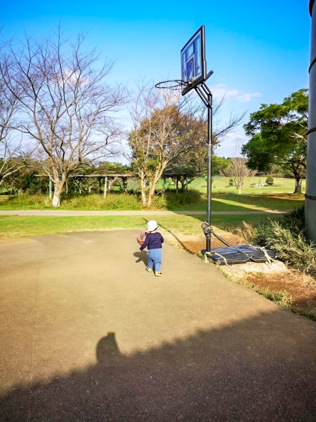バスケットコートでボール遊びをする子供